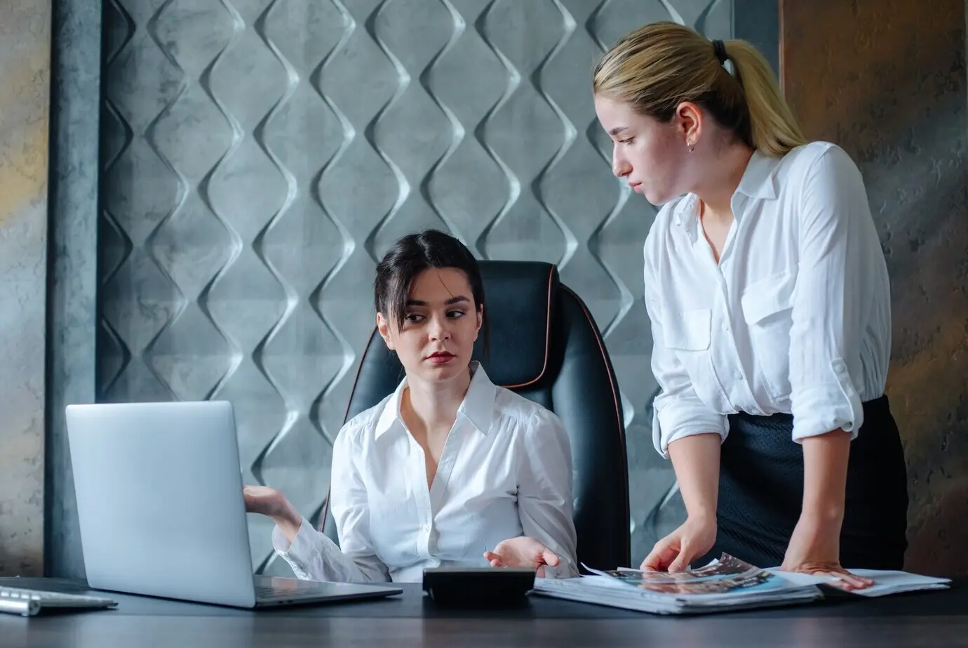 Молодая бизнес-леди, женщина-директор, сидит за офисным столом; недовольна рабочим процессом; деловая встреча, работа с коллегой, решение бизнес-задач, концепция офисного коллектива.